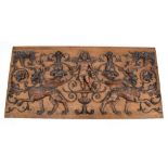 An Italian carved walnut panel featuring Cupid flanked by griffins amongst foliate scrolls,
