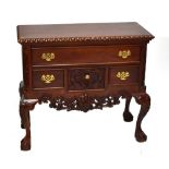 A reproduction lowboy with carved edge above three short and one long drawer on cabriole supports,