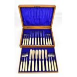 An Edwardian oak cased set of twelve Edwardian hallmarked silver bladed fish knives and forks,