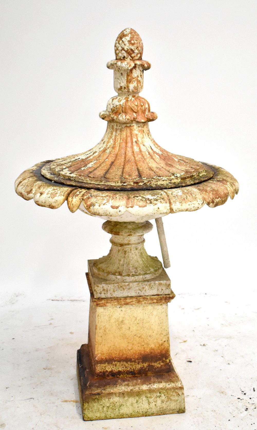 A 19th century cream painted cast iron urn with water fountain fixture, the cover with pine cone