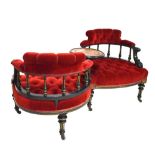 A Victorian ebonised conversation seat with upholstered red button back, each chair surrounding a