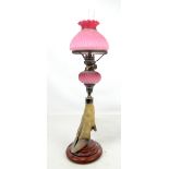 A silver plated candlestick on taxidermy hoof base with a pink glass oil lamp conversion, height