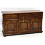 A reproduction oak sideboard with three drawers above three panelled cupboard doors, raised on block