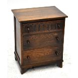 A reproduction oak chest of drawers of small proportions, with three central drawers and raised on