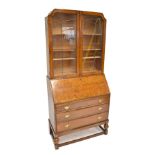 An early 20th century oak bureau bookcase, the upper section with shaped top and twin leaded