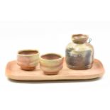 MASANOBU IZUMIHARA; an anagama fired stoneware sake set comprising jug, pair of cups and rectangular