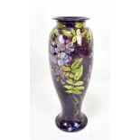 AGNES E M BAIGENT FOR ROYAL DOULTON FAIENCE; a footed cylindrical vase, decorated with wisteria