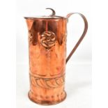 A Scottish Arts and Crafts copper water jug repoussé decorated with stylised roundels and motifs,