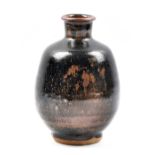 JIM MALONE (born 1946); a stoneware bottle covered in tenmoku breaking to kaki glaze, impressed JM