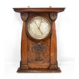 An Arts and Crafts carved oak wall barometer with central silvered dial, flanked by two carved