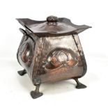 An Arts and Crafts copper log bucket of square form, relief decorated with central floral sprays,