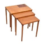 A teak nest of three graduated coffee tables, the largest table with inset tile panel.