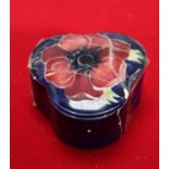 A Moorcroft blue ground anemone pattern trefoil shaped lidded pin dish, diameter 7cm (af).