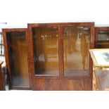 An Art Deco mahogany break-front display cabinet with four bevelled glass doors and twin cupboard