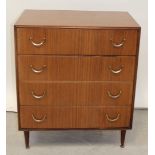 A 1960s teak chest of four long graduated drawers with brass swing handles on tapering legs with