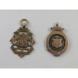 A 9ct gold prize fob, approx 5.5g and a silver on gold prize fob (2).