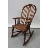 A late 18th century elm-seated Windsor rocking chair with crinoline stretcher.