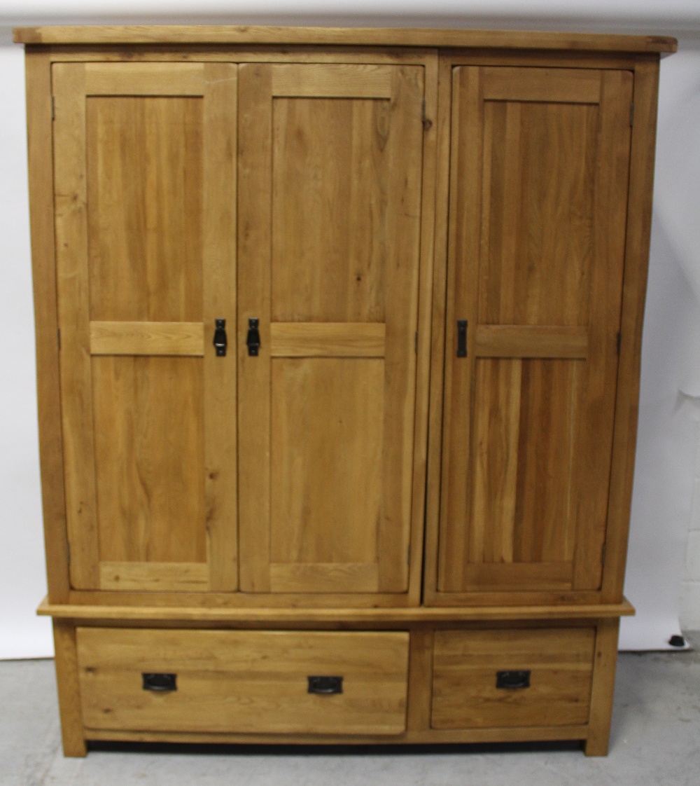 A modern oak bedroom suite comprising light oak triple wardrobe on two-drawer base, height 195cm,