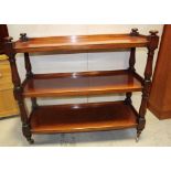 A 19th century mahogany three-tier side buffet separated by baluster supports on steel wheels,
