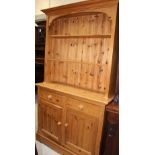 A stripped pine kitchen dresser with stepped shaped top enclosing two shelves over two-drawer,