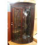 A 19th century mahogany bow-front hanging corner cabinet with twin astragal glazed doors and blind