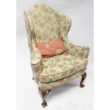 A Queen Anne style wing-back armchair upholstered in woven poppy and floral material,