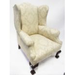 A Georgian-style wing-back armchair upholstered in a woven cream material,