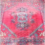 An Eastern-style floor rug with stylised decorations on a red ground.