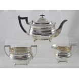 A George V hallmarked silver three-piece tea service with cast beaded rim, raised on four ball feet,