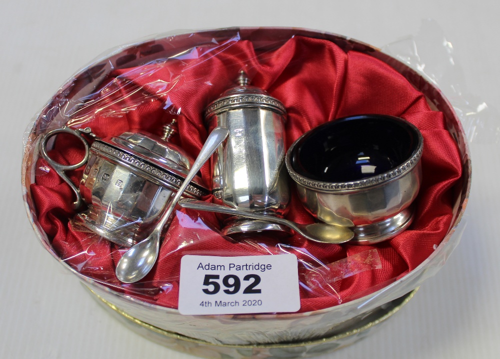 A George V hallmarked silver cruet set of squat form with panelled body comprising lidded mustard,