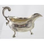 A George III hallmarked silver sauce boat with piecrust edge raised on three hoof feet,