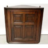 An oak wall-hanging corner cupboard, the single panelled door enclosing two shelves,