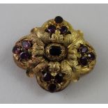 A hollow yellow metal brooch of quatrefoil form with engraved oak leaves set with thirteen
