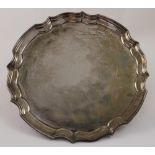 An Elizabeth II hallmarked silver piecrust edge salver raised on three scroll feet, JG Ltd,