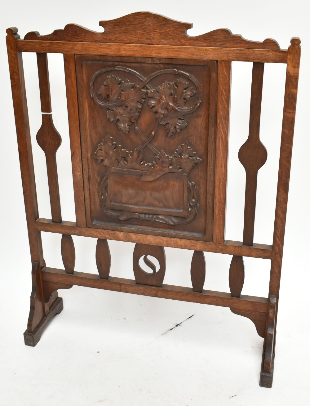 An Arts and Crafts carved oak fire screen, the central panel carved with oak leaves, height 92cm.