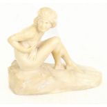 An Art Deco carved alabaster figurine modelled as a nude lady seated on rocks, apparently
