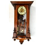 A late 19th/early 20th century walnut cased Vienna style wall clock, the surmount with carved mask