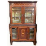 An Edwardian mahogany and inlaid display cabinet, the upper section with twin glazed doors enclosing