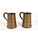 A pair of early 19th century copper mugs with loop handles, scrolling thumbpiece and tapering