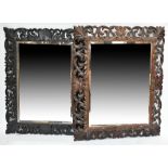 Two late 19th century Black Forest style carved oak wall mirrors with bevelled glass, larger