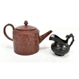 An 18th century redware teapot with acorn finial and textured geometric detail, impressed pseudo