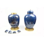 A pair of decorative ginger jars and covers, decorated with gilt landscape scenes on a powder blue