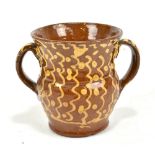 An 18th century slipware loving cup with twin handles and stylised decoration throughout,