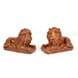 A pair of early 19th century crudely modelled brown glazed recumbent lions each with hollowed