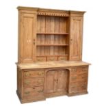 A Victorian pine dresser with boarded plate rack above three drawers flanked by twin cupboard doors,