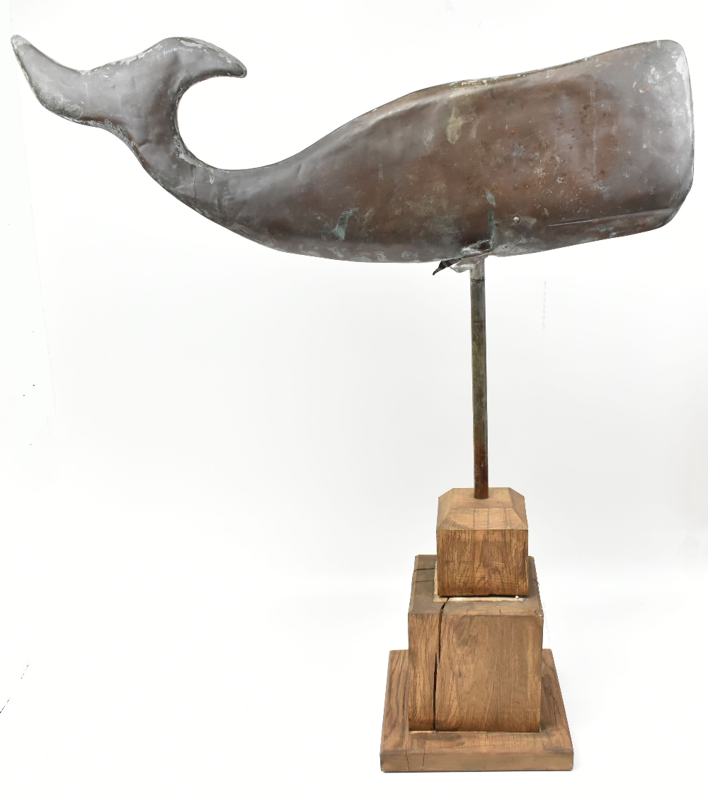 A late 19th century American folk art copper weather vane modelled as a whale, raised on wooden