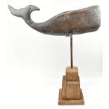 A late 19th century American folk art copper weather vane modelled as a whale, raised on wooden
