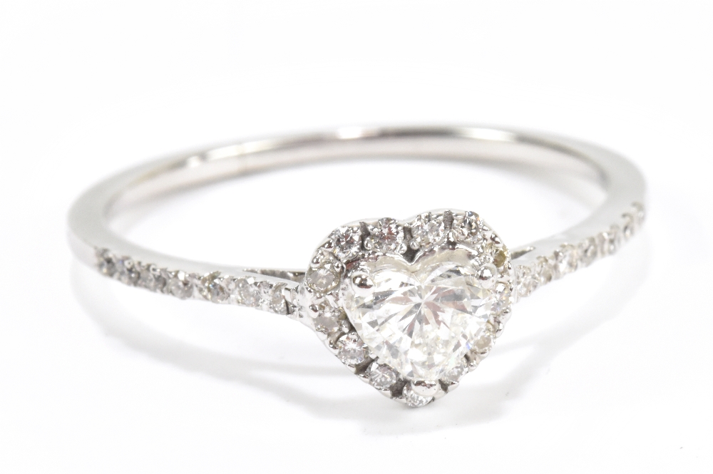 An 18ct white gold diamond ring with heart shaped principal stone within a border of diamonds,
