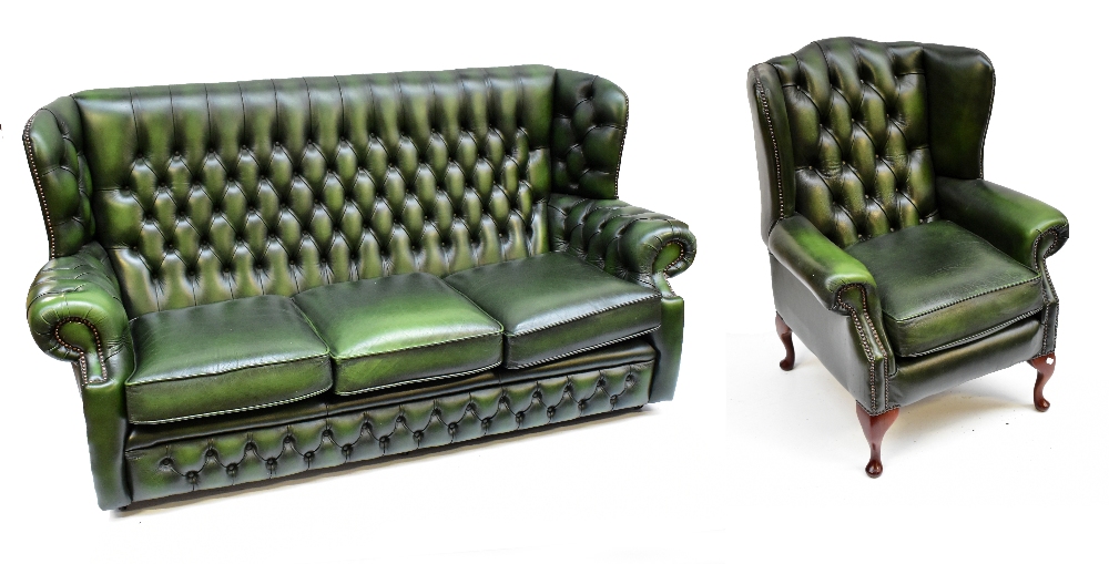 A green leather button upholstered wing back three seater settee with matching chair on cabriole