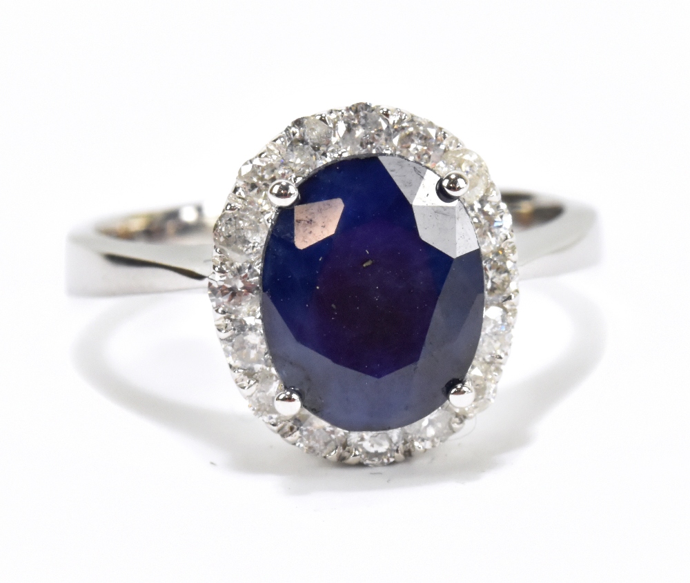 A white metal diamond and sapphire cluster ring, the modified brilliant cut sapphire weighing approx